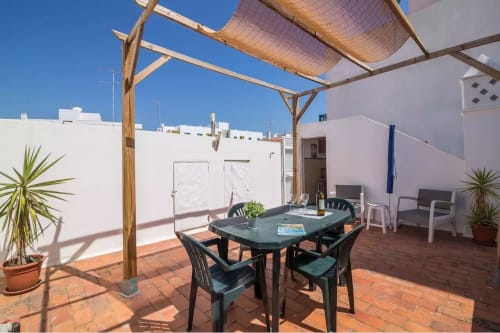 Terraço na cobertura das Armação Beach Residences com mesa de jantar, pérgola de madeira e vista para a cidade de Armação de Pêra
