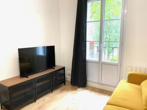 Séjour moderne avec canapé jaune, télévision écran plat et portes vitrées donnant sur la verdure à Residence Disneyland