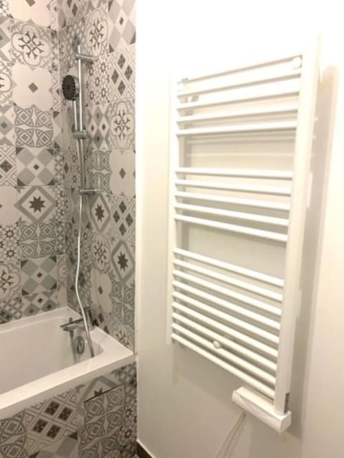 Salle de bains moderne avec carrelage à motifs, radiateur sèche-serviettes blanc et espace douche à la Résidence Disneyland Place Toscane