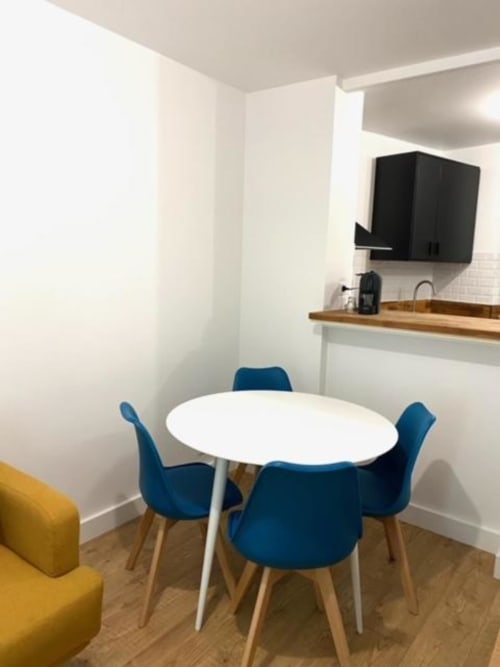 Salle à manger moderne avec table ronde blanche, chaises bleues et kitchenette dans un appartement de Disneyland Paris