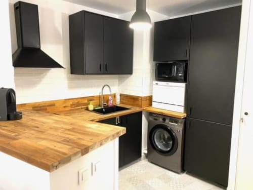 Cuisine moderne avec meubles noirs, plan de travail en bois, évier, cuisinière, lave-linge et micro-ondes à Disneyland Paris