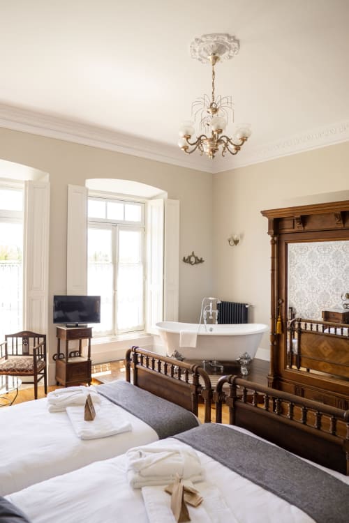 Suite de dormitorio elegante en La Venta de Miyares con bañera exenta, camas gemelas, muebles de madera y vistas al jardín