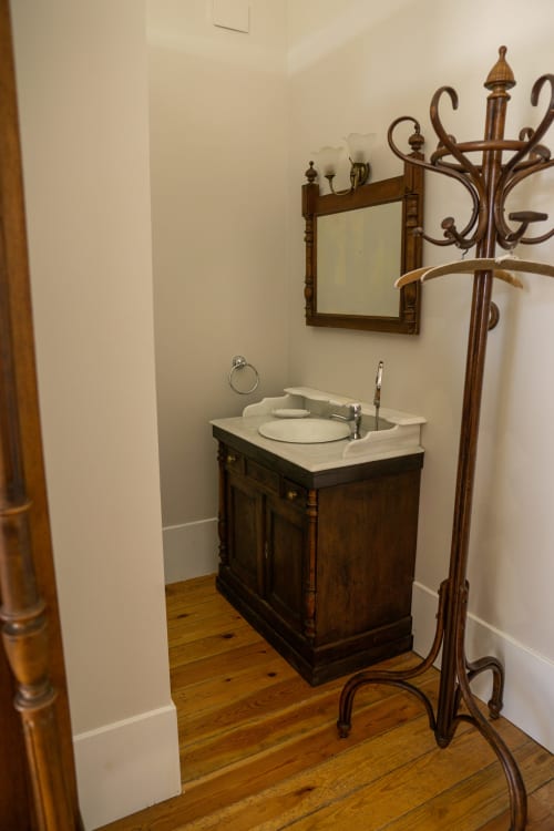 Baño vintage en la Habitación Miyares de La Venta de Miyares con tocador de madera oscura, encimera de mármol blanco y perchero decorativo