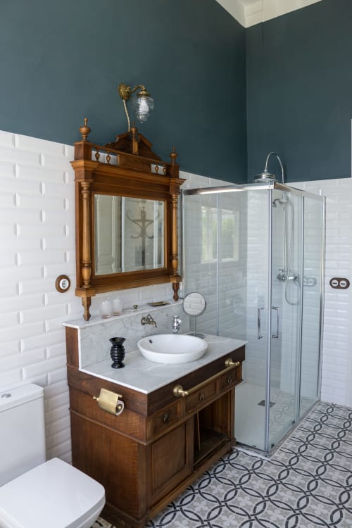 Elegant bathroom in El Palacio room at La Venta de Miyares with vintage wooden vanity, marble countertop, and modern shower