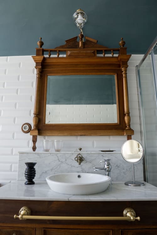 Elegant bathroom with wooden vintage mirror above marble sink in El Palacio room at La Venta de Miyares
