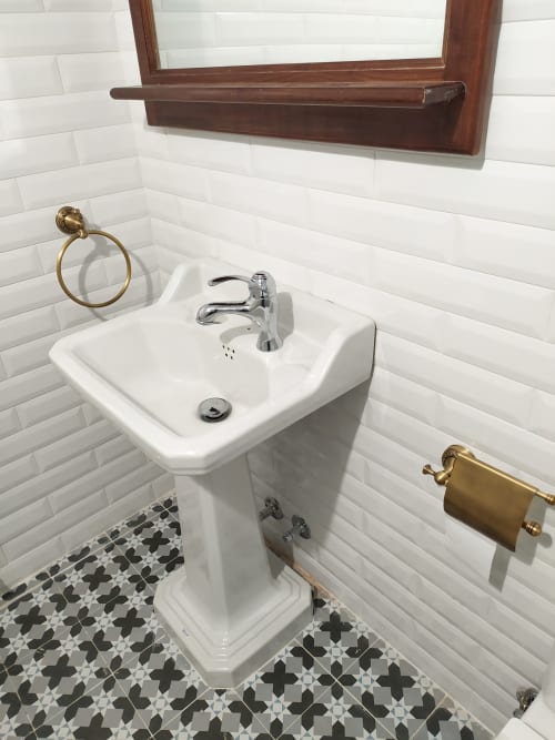 Pedestal sink with chrome faucet in El Pando room bathroom at La Venta de Miyares, white subway tile walls, patterned floor