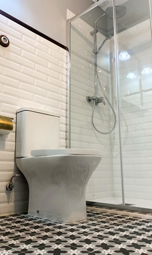 Modern bathroom in El Pando room at La Venta de Miyares with white subway tile, toilet, rainfall shower, and patterned floor