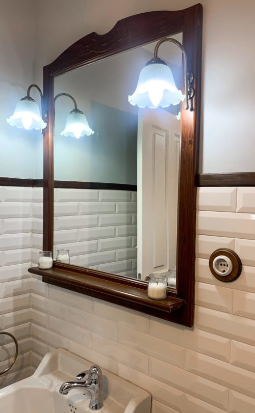 Elegant bathroom mirror with dark wood frame, white subway tile walls, and decorative sconces at La Venta de Miyares hotel