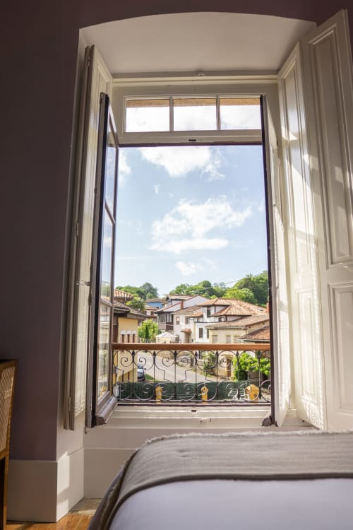 Puertas abiertas de la terraza de la Suite Pintueles en La Venta de Miyares revelan vistas de montaña y tejadillos de pueblo asturiano tradicional.