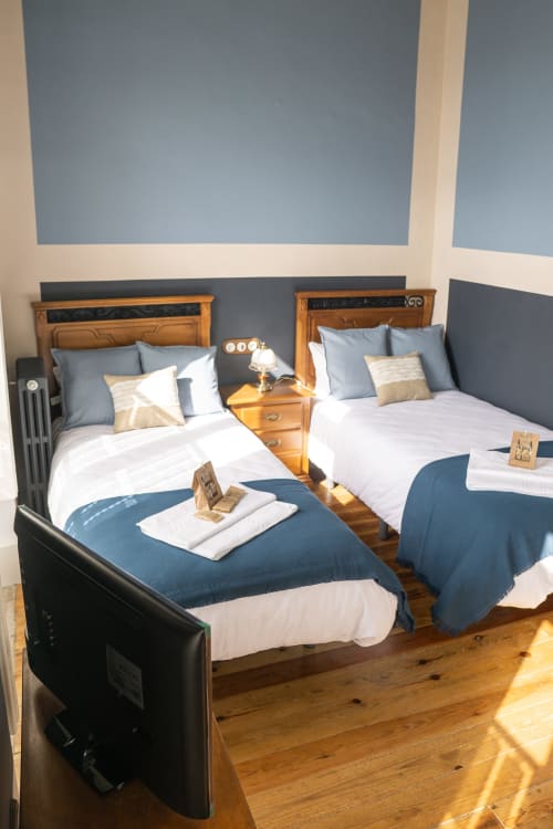 Camas gemelas con ropa de cama azul y blanca en la Suite Pintueles del hotel La Venta de Miyares en Asturias