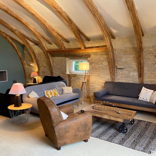 Salon rustique moderne aux Lumieres Du Causse avec poutres en bois, murs en pierre et mobilier contemporain