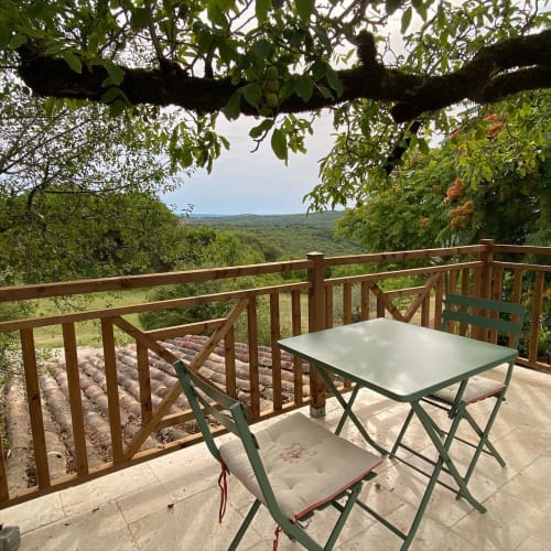 Terrasse panoramique des Lumieres Du Causse avec table de restaurant surplombant le paysage verdoyant du Causse, Bellefont-La Rauze