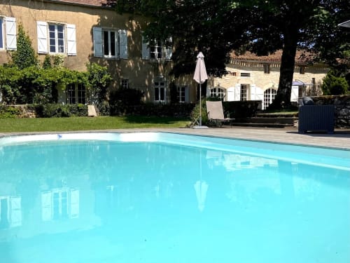 Piscine turquoise aux Lumières du Causse avec transats, parasol et bâtisses en pierre à Bellefont-La Rauze, France