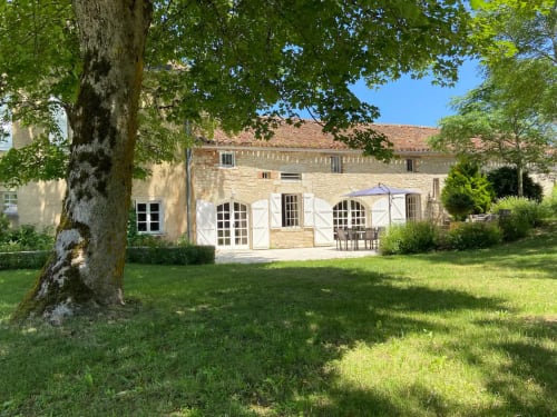 Cottage en pierre avec volets blancs et pelouse verte aux Lumières du Causse, Bellefont-La Rauze