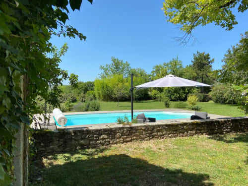 Piscine turquoise avec parasol blanc et transats à Les Lumieres Du Causse B&B à Bellefont-la-Rauze, France