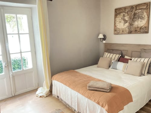 Chambre lumineuse au B&B Les Lumieres Du Causse avec lit queen-size, plaid terracotta et portes-fenêtres donnant sur le jardin