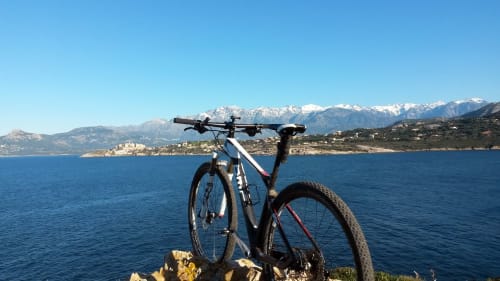 VTT dominant la mer Méditerranée près de Corbara, France avec les Alpes enneigées au loin