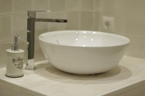 Lavabo blanco moderno con grifo cromado y dispensador de jabón en Casa Tapiolas en Molló