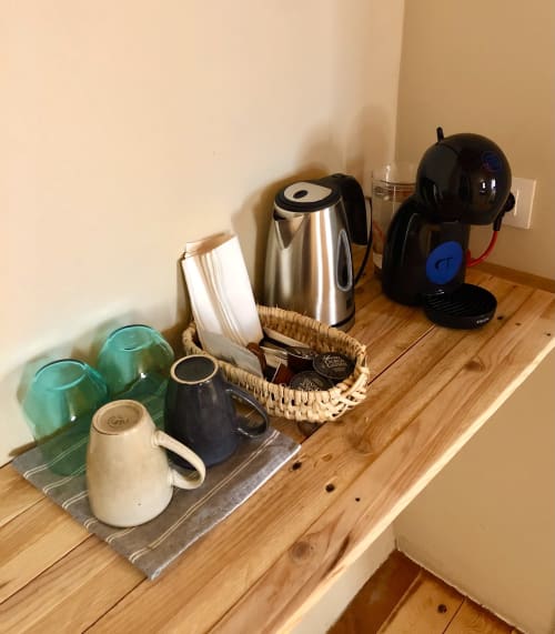 Estación de café en Casa Tapiolas de Molló con tetera, tazas y cafetera sobre estante de madera