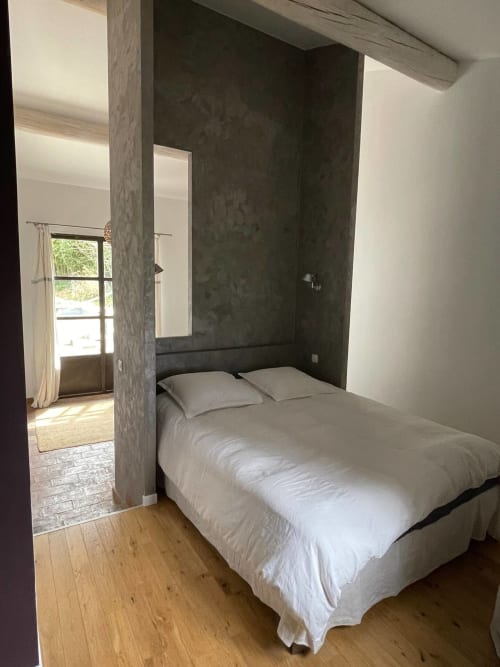 Chambre moderne du gîte Campagne d'Albert à Marseille : literie blanche, mur d'accent foncé, parquet et vue sur le jardin