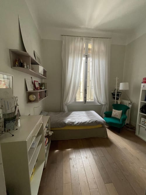 Chambre lumineuse au gîte Campagne d'Albert à Marseille avec lit, fauteuil turquoise, parquet et vue sur le jardin