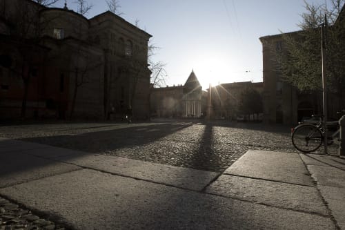 Historic Bologna piazza at sunrise with medieval stone buildings and church, near L'Appartamento Giusto BnB
