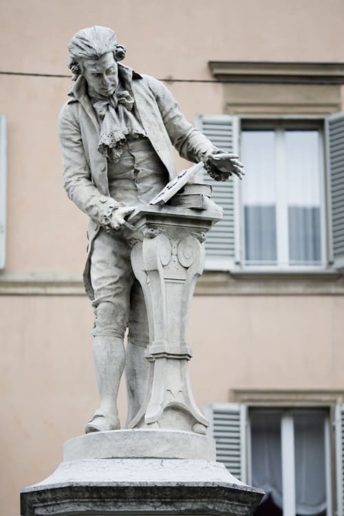 Stone statue of man reading books in Bologna courtyard near L'Appartamento Giusto