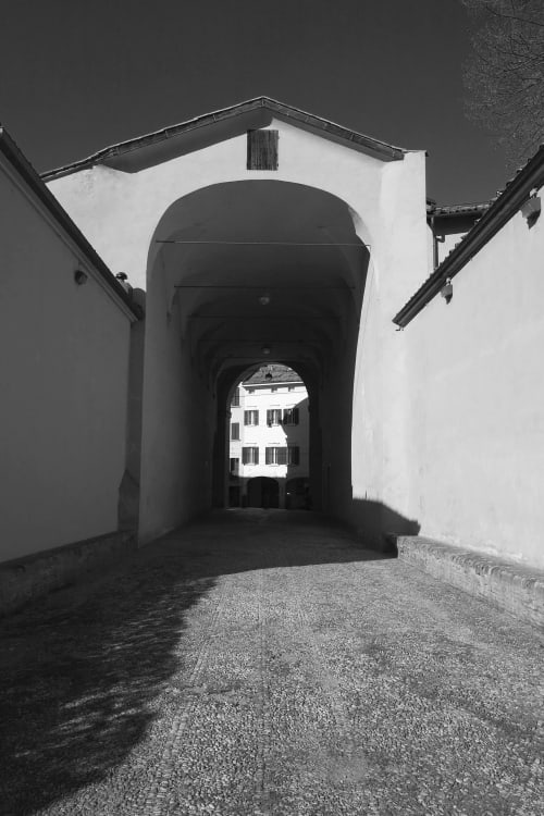 Arched stone passageway leading to a building in Bologna, Italy - L'Appartamento Giusto entrance hallway