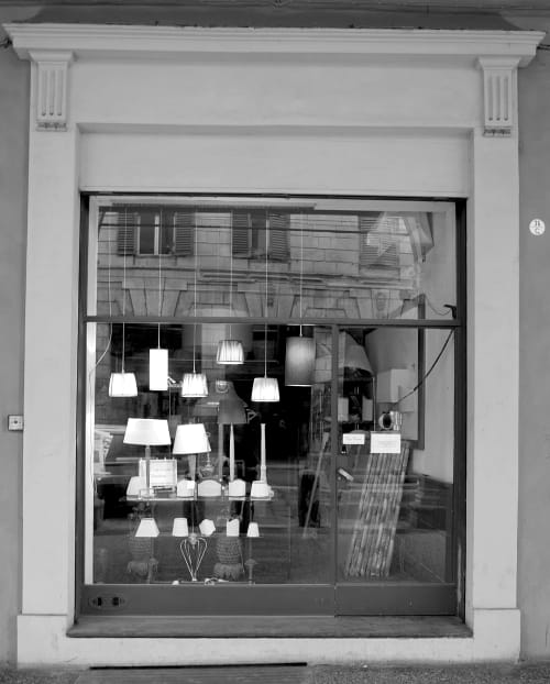 Storefront window of L'Appartamento Giusto, a boutique B&B in Bologna, displaying modern pendant lamps and furniture