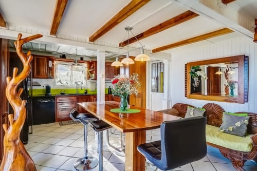 Cuisine-salle à manger moderne aux Terrasses Du Volcan avec poutres en bois, touches de vert et sculpture en bois à Tampon