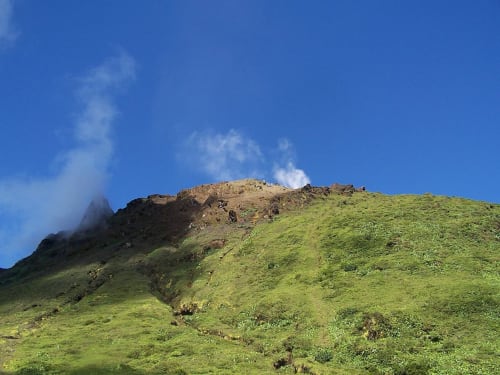 Versant verdoyant avec pic volcanique rocheux sous ciel bleu près du Moule, Guadeloupe