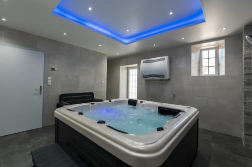 Spa moderne à La Vallée Joly avec bain à remous éclairé, plafond bleu et murs carrelés gris au