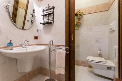 Bagno in comune presso il Dormire Assisi B&B ad Assisi, con lavabo su colonna, WC e doccia rivestita in piastrelle bianche e legno