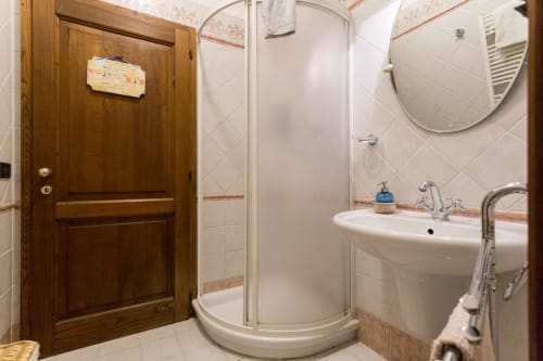 Bagno della Dormire Assisi B&B Assisi con doccia angolare, lavabo bianco, specchio e porta in legno