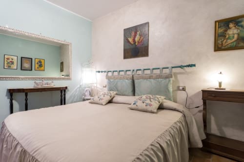Camera elegante presso il B&B Dormire Assisi ad Assisi con biancheria crema, dettagli turchesi e opere d'arte tradizionali