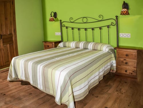Dormitorio verde brillante en el hotel Turismo en Sanabria con ropa de cama rayada, cama de hierro forjado y mesitas de noche de madera