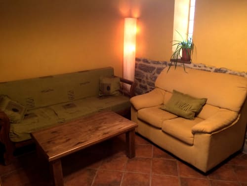Acogedora sala de estar en el hotel Turismo en Sanabria de Zamora con sofá color crema, mesa de madera e iluminación ambiental cálida