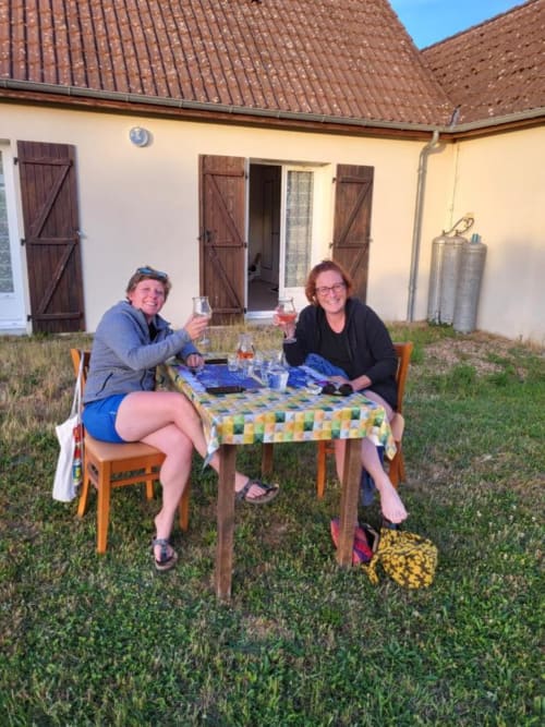 Deux femmes trinquent avec des verres de vin à une table en plein air dans le jardin de l'Hôtel Cheverny La Vie Est Belle, France