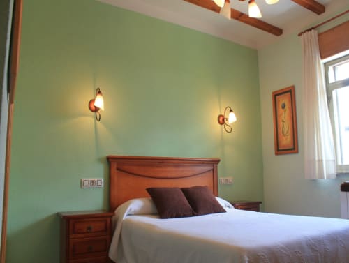 Quarto brilhante em Turismo en Sanabria em Zamora com paredes verde menta, cama de madeira e arandelas geminadas