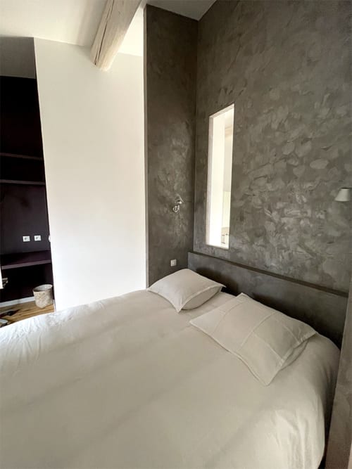 Chambre moderne à la Campagne d'Albert B&B à Marseille, avec literie crème, murs gris texturés et miroir intégré