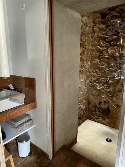 Salle de bain avec douche et murs en pierre rustique à l'appartement Campagne d'Albert à Marseille