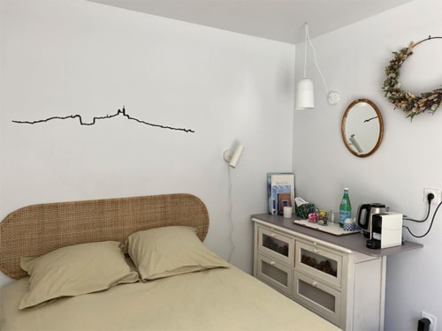 Chambre accueillante à la Campagne d'Albert B&B à Marseille avec tête de lit en rotin, linge beige et équipements modernes incluant bureau