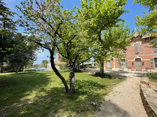 Jardins verdoyants avec arbres matures à Campagne d'Albert, gîte marseillais aux bâtiments de brique rouge et atmosphère paisible