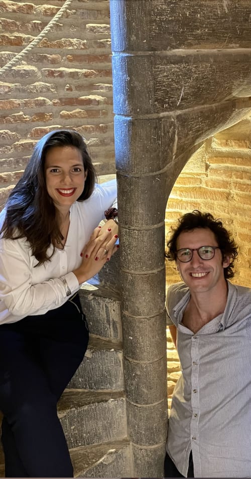Due ospiti sorridenti a La Tour Du Capitole BnB a Toulouse, in posa davanti all'architettura storica in pietra