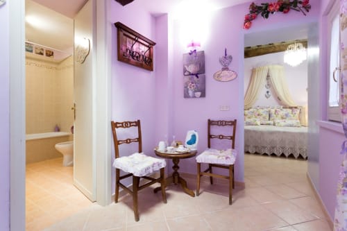Camera con tema lavanda presso Dormire Assisi B&B ad Assisi, con sedie in legno, dettagli decorativi a forma di cuore e bagno interno