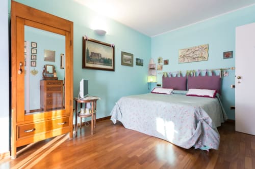 Cozy bedroom in Assisi B&B with turquoise walls, purple headboard, wooden furniture, and garden views