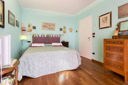 Bright bedroom at Dormire Assisi B&B in Assisi with turquoise walls, floral bedding, wooden furniture, and garden view