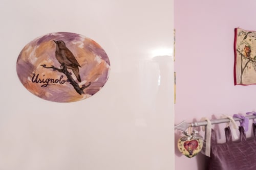 Charming bedroom decoration at Dormire Assisi featuring hand-painted bird artwork and purple floral accents in Camera
