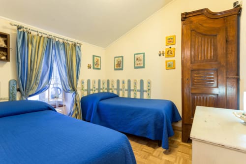 Camera Philip presso il Dormire Assisi B&B ad Assisi con letti gemelli dalle coperte blu, guardaroba in legno e pareti gialle