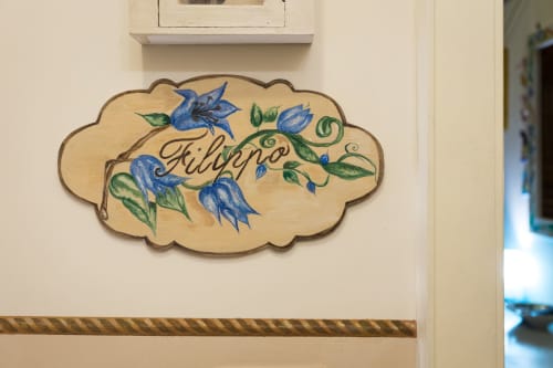 Cartello decorativo in legno con scritta 'Filippo', decorato con fiori blu e foglie verdi presso la struttura Dormire Assisi B&B ad Assisi, Italia